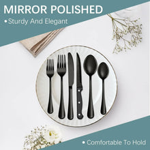 Mirror-polished black stainless steel silverware set on plate: forks, knives, spoons