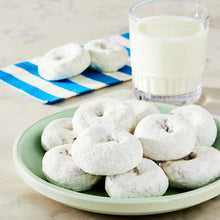 Powdered sugar mini donuts on a plate with a glass of milk