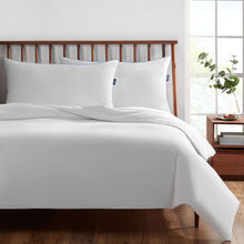 White king bed pillows with blue piping, set on a bed