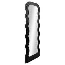 Tall floor mirror with sculpted black wavy frame and reflective glass