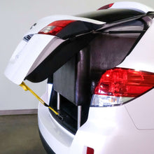 Yellow trunk strap securing a load in open car trunk with metal end loops