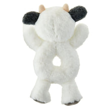 White plush cow rattle with black ear tips and dark spots on body