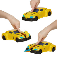 Yellow Bumblebee-style vehicle toy being transformed by hands, with black wheels.