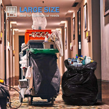 Black trash bag liner hanging over a bin, with another bag nearby