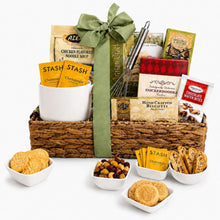 Comfort gift basket with soup, tea, biscuits, snacks, a mug, whisk and green ribbon