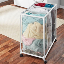 Mesh laundry sorter cart with three compartments holding folded clothes and caster wheels