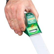 Hand holding green manual packaging tape dispenser dispensing clear tape strip