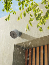 Outdoor security camera mounted on a wall with raindrops near the lens