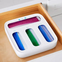 White bag dispenser in drawer with blue, green, and pink bag rolls