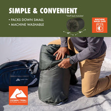 Doublewide sleeping bag packed into a dark stuff sack on a camping surface