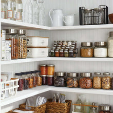 Glass spice jars with silver lids on kitchen shelves for dry storage