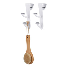 White over-the-door rubber grip hooks holding a wooden cleaning brush