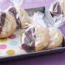 Clear treat bags holding round cookies, tied and packed on a tray