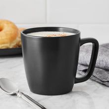 Matte black stoneware mug with handle and top filled with coffee