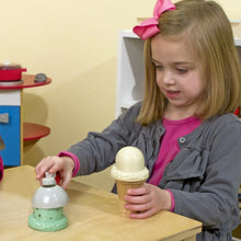 Child holding a green ice cream cone topped by a scoop piece