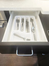 Stainless steel flatware pieces in an organizer tray inside a drawer