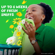 Green liquid laundry detergent bottle near a smiling person with a green towel
