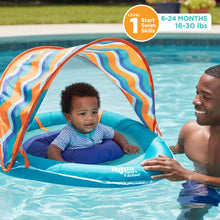 Infant in blue baby pool float with striped canopy during outdoor swim