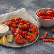 Spicy breaded snack chips on plate with dipping sauce and lemon wedge