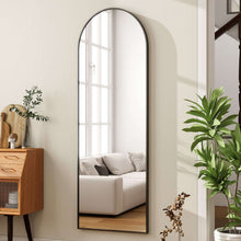 Black arched wall mirror with slim frame, reflecting a couch and window light