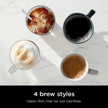 Single-serve coffee brewer with four filled cups of coffee arranged around it.