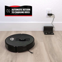 Black robot vacuum returning to charging dock on light wood floor