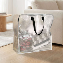 Transparent storage bag with zipper and black handles, filled with folded blankets