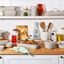 Taupe stoneware bake-and-store set on kitchen counter with multiple bowls and lids