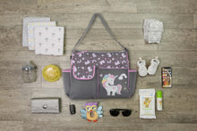 Gray unicorn-print diaper bag with accessories laid out on a light floor