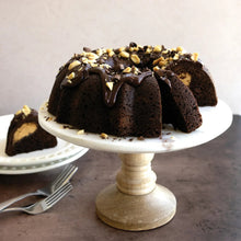 Chocolate bundt cake on pedestal stand with chopped nut topping