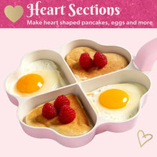 Heart-shaped fry pan with four compartments holding eggs and small pancakes