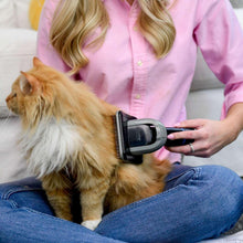 Pet grooming vacuum nozzle in use on a dog, handheld unit