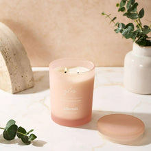 Glow scented spa jar candle in frosted pink glass, lid beside jar, two wicks lit