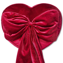 Heart-shaped red decorative pillow with ruched center bow and draped hanging tails.
