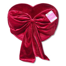 Heart-shaped red decorative pillow with ruched bow and fabric label tag on the side.