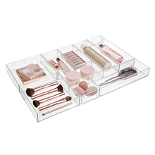 Clear 9-compartment drawer organizer tray filled with cosmetics and makeup brushes.