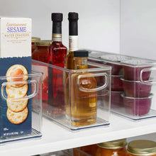 Clear deep storage bins set with handle fronts holding bottles, crackers, and jars