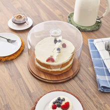 Wood cake plate with clear dome lid holding a round cake with berries