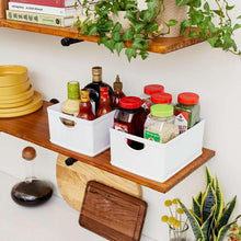 White stacking organization bins on wood shelf holding bottles, jars, and spices