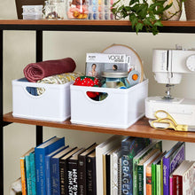White stacking organization bins on shelf with towels, books, and small household items