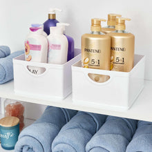 White stacking bins holding toiletries and lotion bottles; integrated side handles
