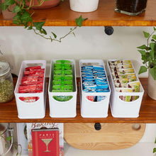 White countertop storage bins holding red, green, blue, and mixed snack items