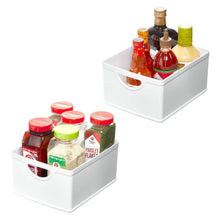 Set of 2 white stacking organization bins with handles, holding pantry bottles and jars