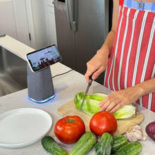 Wireless charging stand with Bluetooth speaker on kitchen counter, phone in use