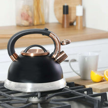 Black tea kettle with copper-toned handle and spout on gas stove, stainless base
