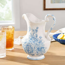 White stoneware pitcher with blue floral pattern, curved handle and spout
