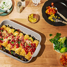 Covered taupe baking dish filled with baked casserole, herbs and sauce
