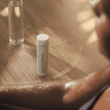 Deodorant stick with white cap, upright on a surface