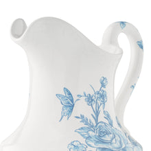 White stoneware pitcher with blue floral and butterfly motif, curved handle