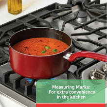 Red nonstick saucepan on gas stove with cooking sauce and herbs